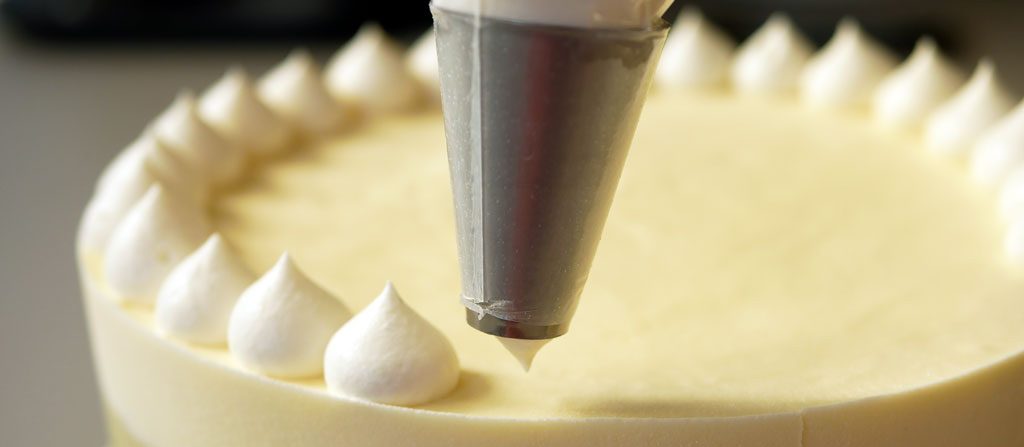 Piping mascarpone frosting on Tiramisu cake
